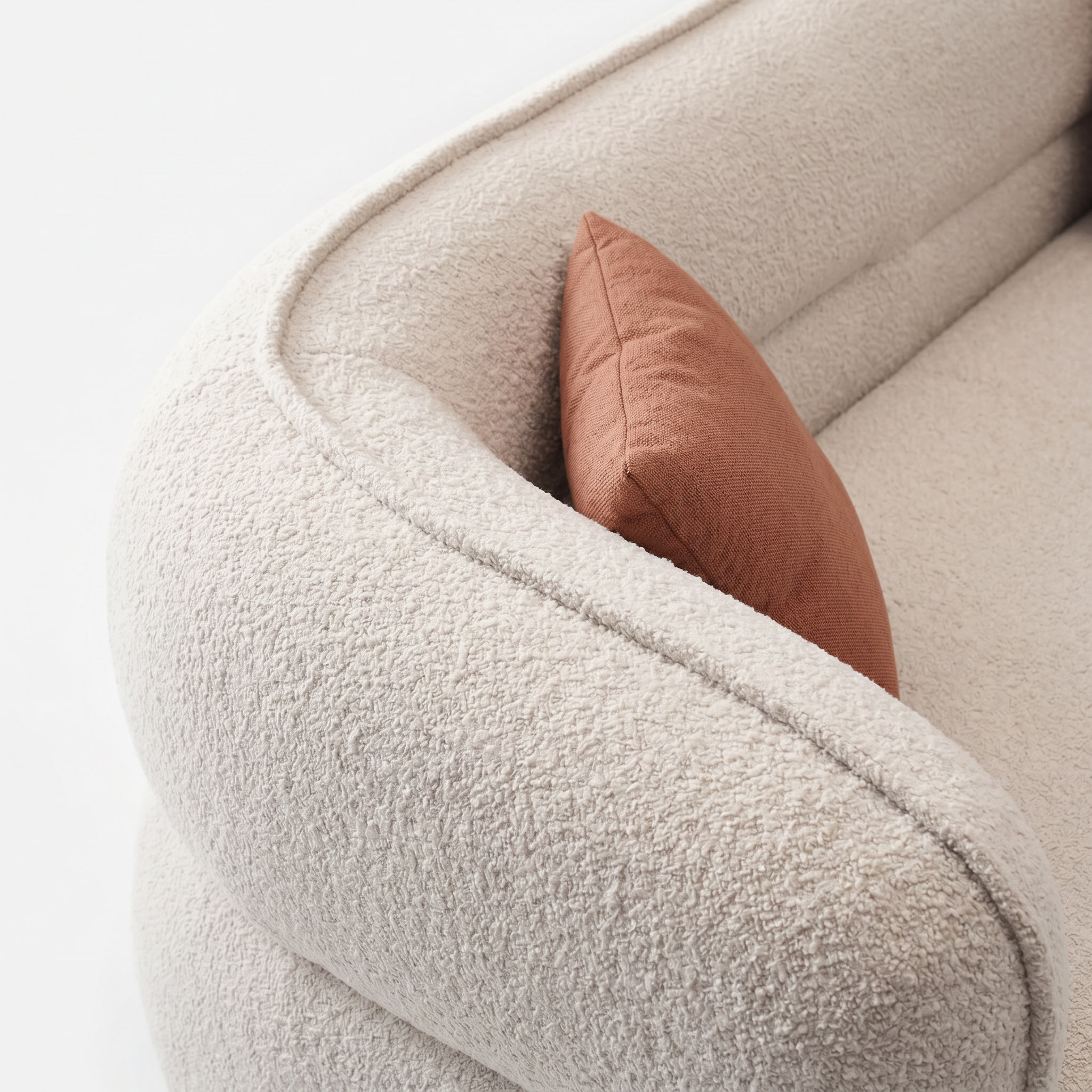 Lune Bouclé Crescent Sofa detail with cream textured upholstery and warm accent pillow