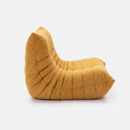 Noma Floor Lounge Chair side view with curved low-profile shape and pleated cushion designshape