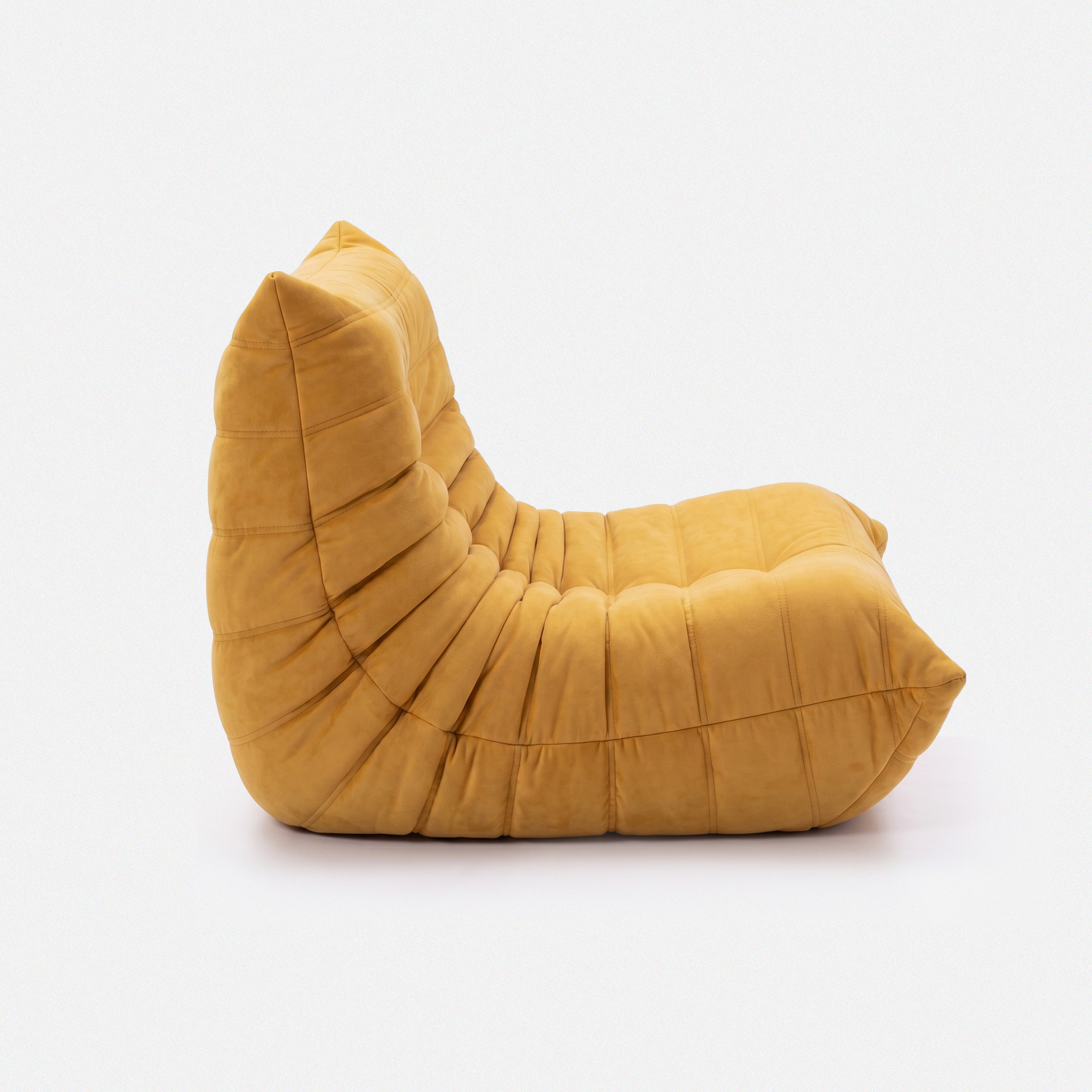 Noma Floor Lounge Chair side view with curved low-profile shape and pleated cushion designshape