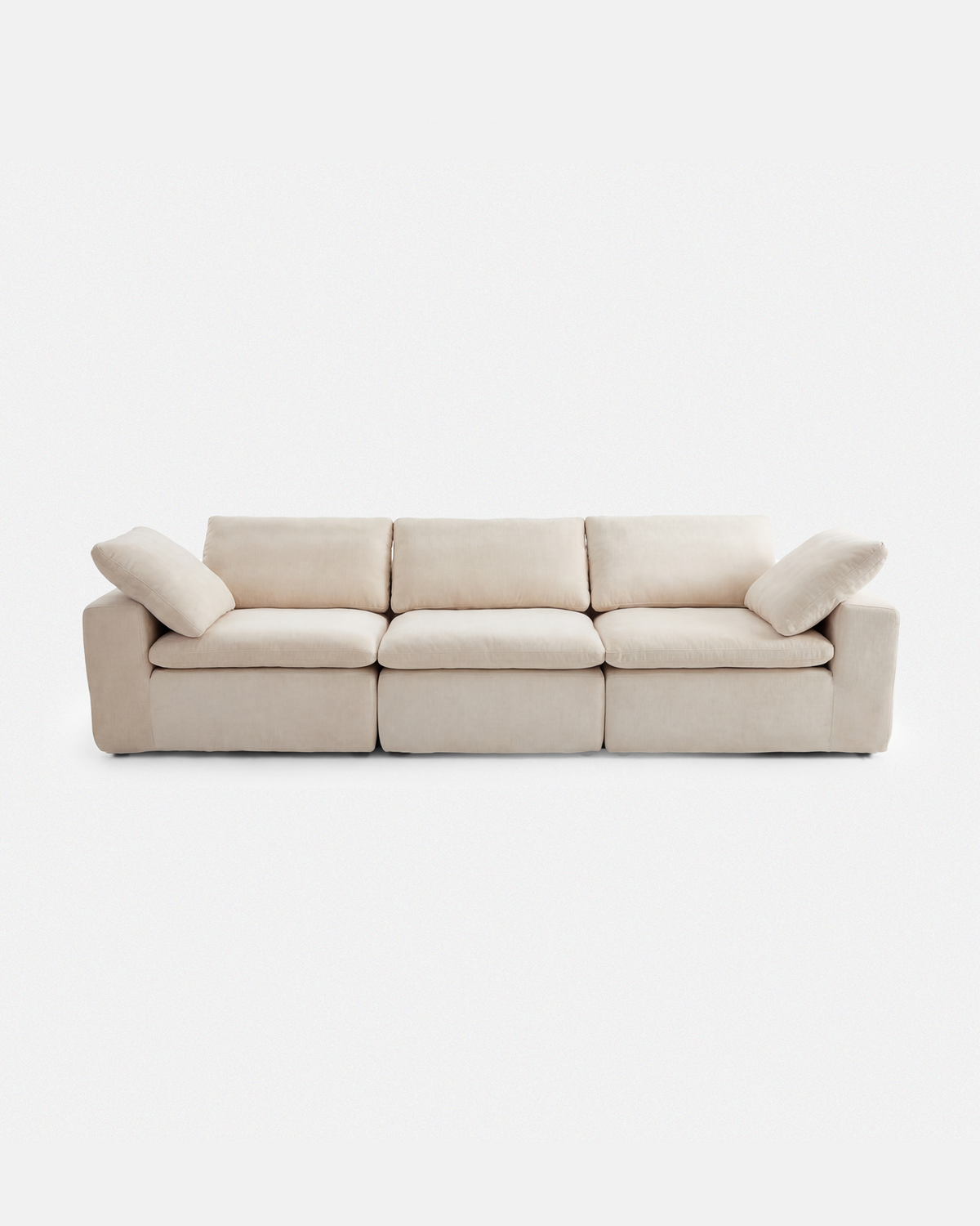 Cream white three-seat modular sofa with loose cushions on a white background