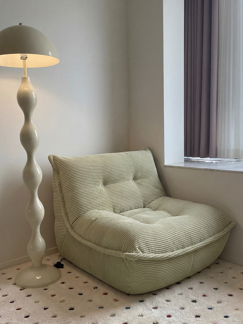 Lune Cream Lounge Chair in Moss styled in a cozy reading corner