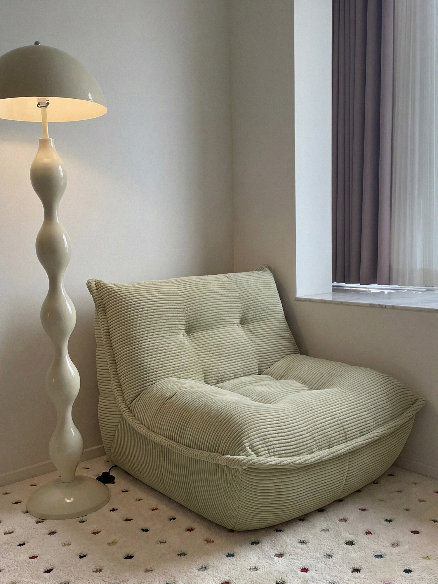 Lune Cream Lounge Chair in Moss styled in a cozy reading corner