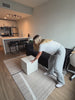 Woman converting the black Milo Corduroy Sleeper Sofa from a sofa into a bed in a modern apartment.

